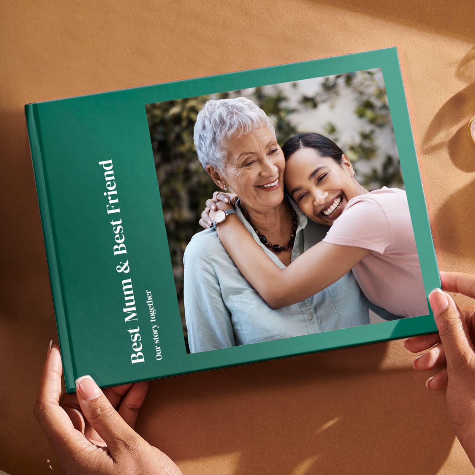 A person holds a Popsa Photo Book titled "Best Mum & Best Friend," featuring two women smiling and embracing on the cover.